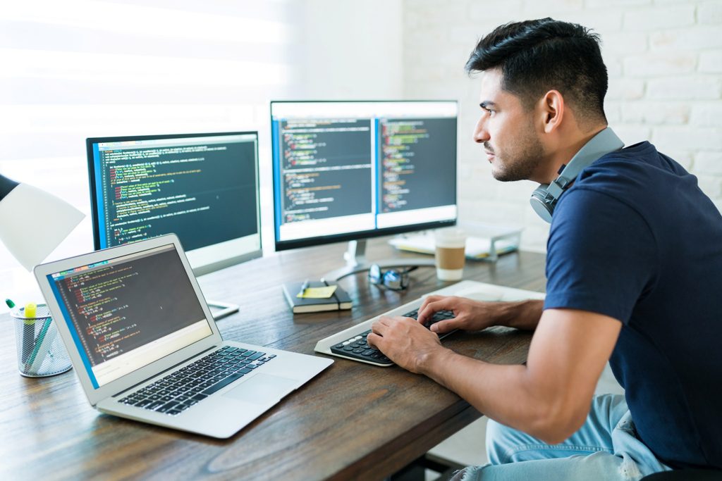 side view attractive hispanic software developer programming using computer while working from home